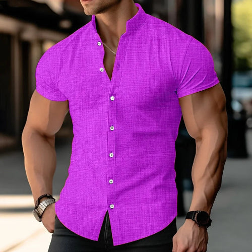 A man wearing a bright purple short-sleeve button-up shirt with a textured grid pattern, shown from the chest down in an outdoor urban setting.
