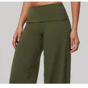 Olive green high-waisted wide-leg yoga pants shown on a model, featuring a double waistband and side pockets, against a solid gray background.