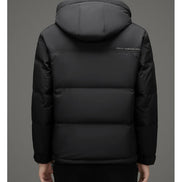 A person shown from the back wearing a black hooded puffer jacket with horizontal quilting and a small white 'HELLO WORLD' text print on the upper back, against a plain gray studio background.