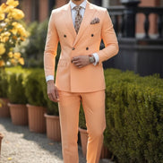 Man wearing a peach suit with a patterned tie and pocket square, standing outdoors.