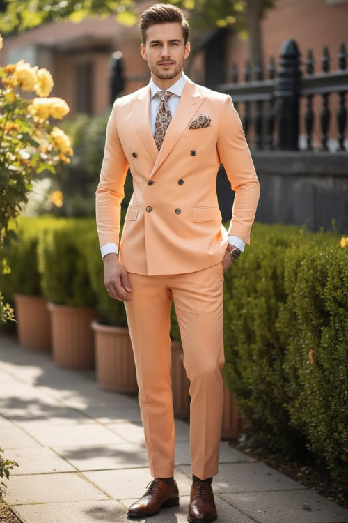 Man wearing a peach suit with a patterned tie and pocket square, standing outdoors.