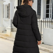 Person wearing a black puffer coat standing on a street.