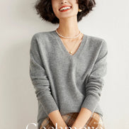 Woman wearing a gray cashmere sweater with 'Cashmere' branding.