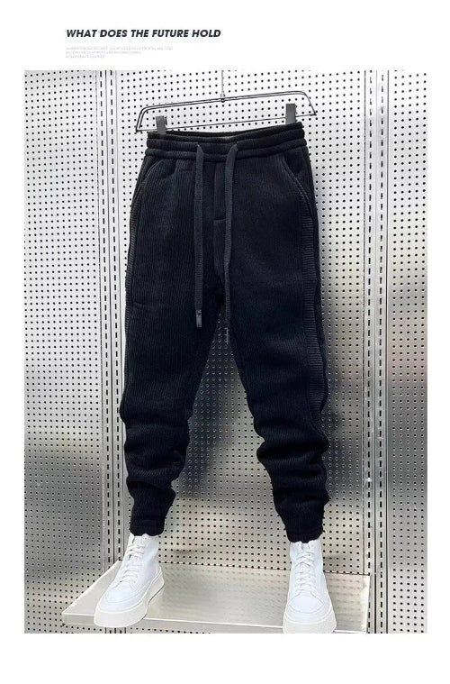 Black baggy sweatpants hanging on a hanger with white sneakers below and a white border around the photo.