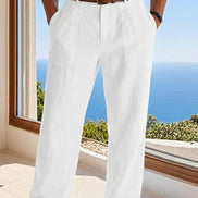 Person wearing white pants with a brown belt, standing by a window with a scenic view.