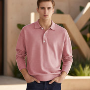 Person wearing a pink long-sleeve polo shirt against a beige background