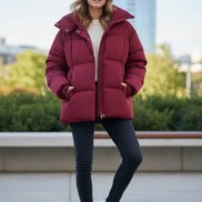 A dark red puffer jacket displayed on a cream-colored mannequin torso against a white wall.