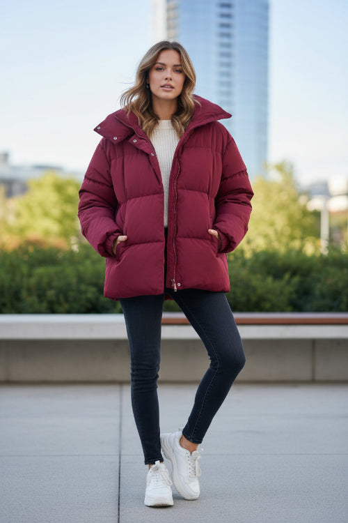 A dark red puffer jacket displayed on a cream-colored mannequin torso against a white wall.