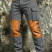 Gray cargo pants with tan contrast panels at the knees and front pockets, flap thigh pockets, and a brown belt against a textured gray background.