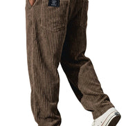 A person wearing brown corduroy pants with a white t-shirt and white low-top sneakers, shown from the waist down against a plain white background.