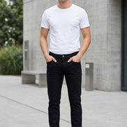Black slim-fit jeans laid flat on a wooden surface, styled with a rope and small props at the edges.