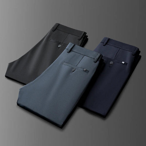 Three pairs of folded men's dress pants in dark gray, charcoal blue, and navy blue, arranged diagonally on a dark gray gradient background.