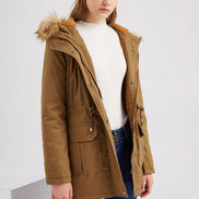 Woman wearing a brown parka coat with fur hood on a white background