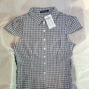 Black and white checkered shirt with a tag on a light gray background