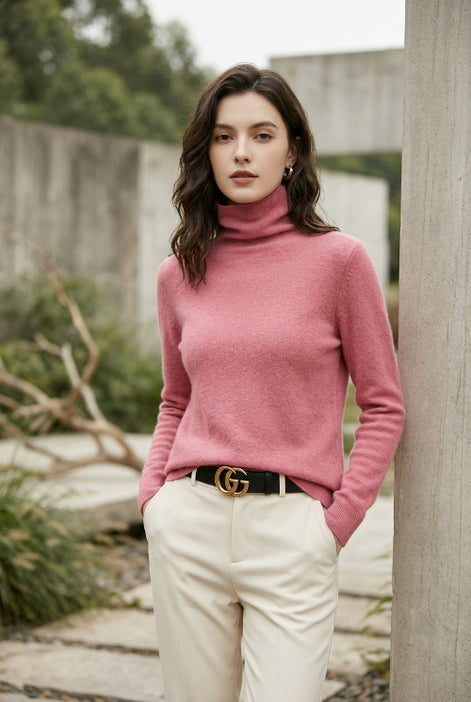 A close-up of a woman wearing a bright pink turtleneck sweater, paired with a black belt featuring a gold double-G buckle.