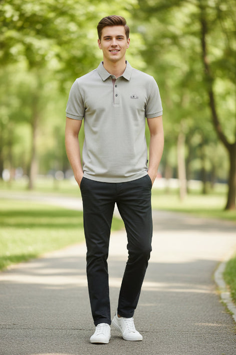 Light gray shirt with a brand logo on a hanger and being held by a hand.