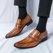 Brown leather shoes with gold accents worn by a person on a white background