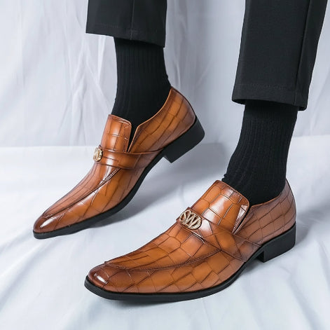 Brown leather shoes with gold accents worn by a person on a white background