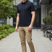 Dark blue shirt with red stitching on a hanger, held by a hand.