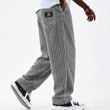 Person wearing gray corduroy pants on a white background