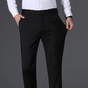 A person wearing black dress pants with a white dress shirt, shown from the chest down against a dark gray studio background.