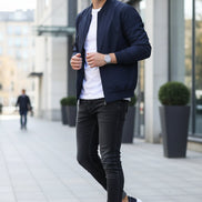 Navy blue sneakers with white soles and red and white stripes on a stone surface.