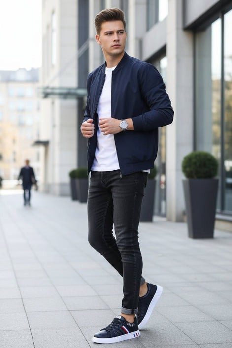 Navy blue sneakers with white soles and red and white stripes on a stone surface.