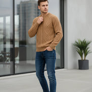 Beige knitted sweater in a black box with a watch on a dark surface