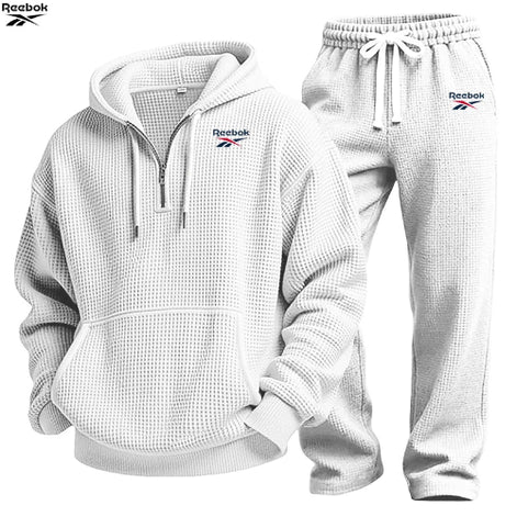 A Reebok two-piece tracksuit set featuring a white waffle-knit pullover hoodie with a half-zip front and matching jogger pants, 