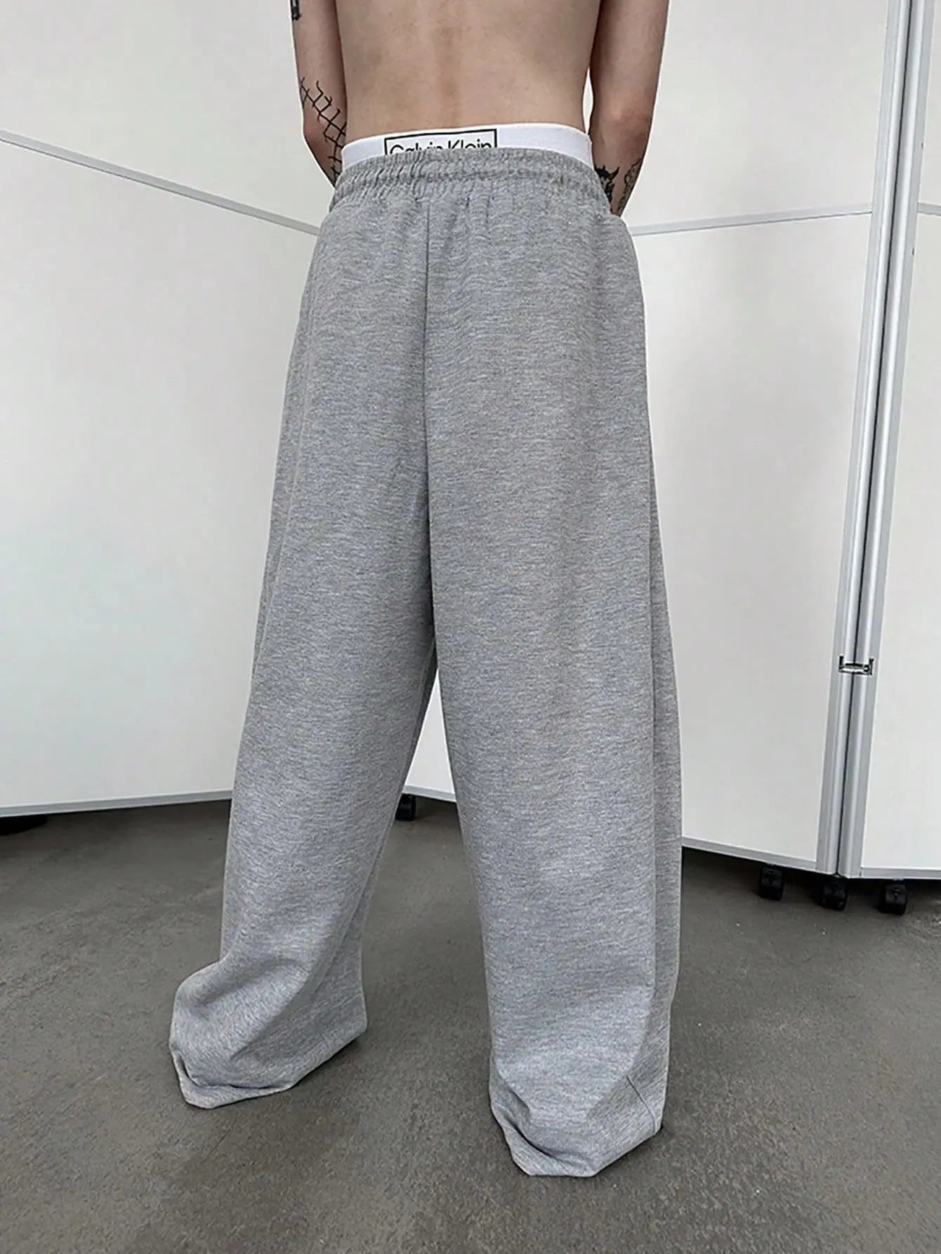 Person wearing gray sweatpants in a minimal indoor setting