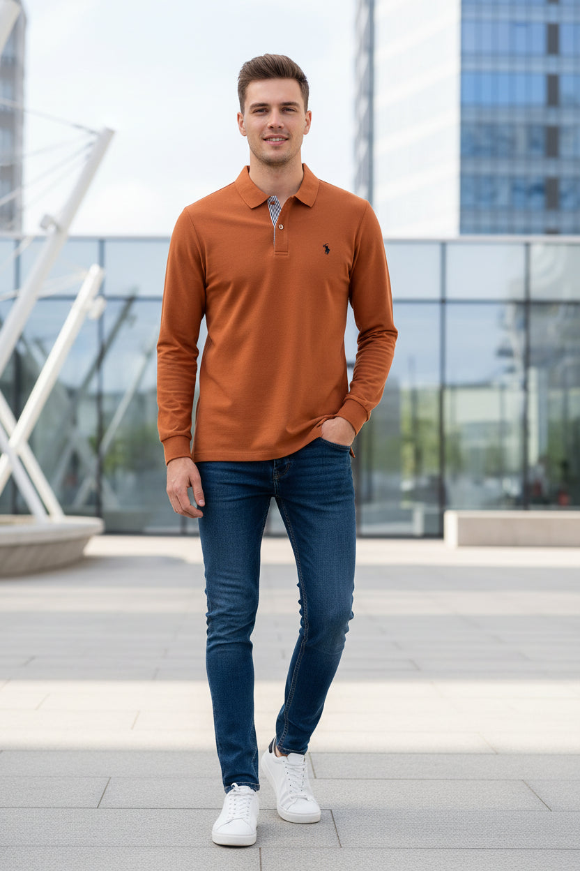 Orange long-sleeve polo shirt on a hanger with other colored shirts in the background.