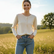 A woman wearing a cream-colored, long-sleeve button-up knit cardigan sweater