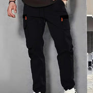 Black cargo pants with cargo pockets and a drawstring waist worn by a man with white sneakers