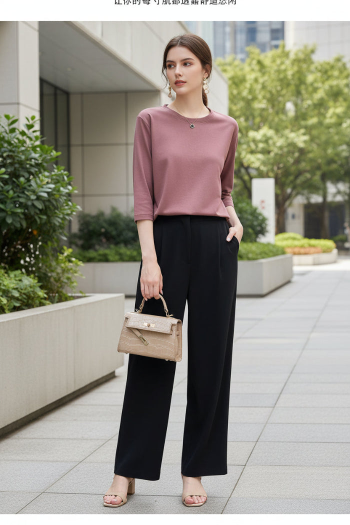 Person wearing a pink top and holding a beige handbag indoors.