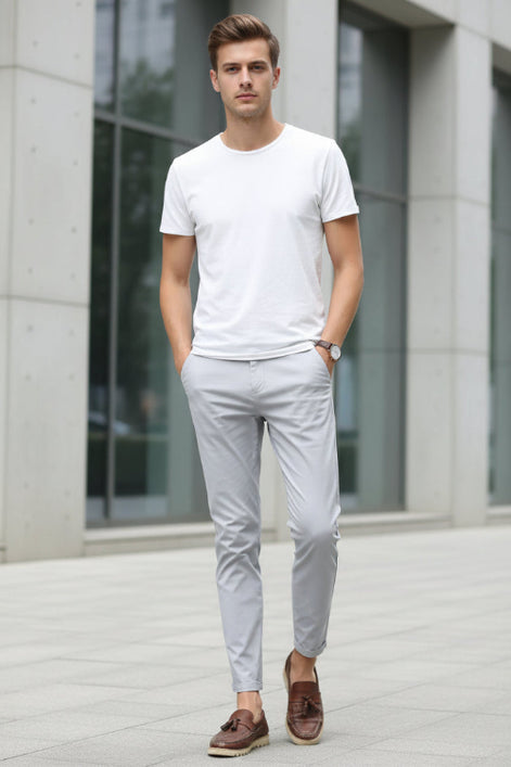 Person wearing light gray pants and brown shoes on a white background