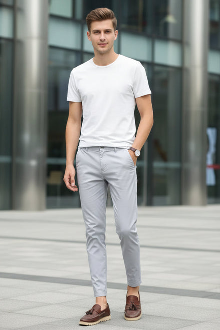 Person wearing light gray pants and brown shoes on a white background