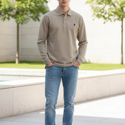 Beige polo shirt with Ralph Lauren logo held by a hand against a blurred background