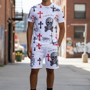 Person wearing white shorts with red crosses and black text, paired with white sneakers on a white background.