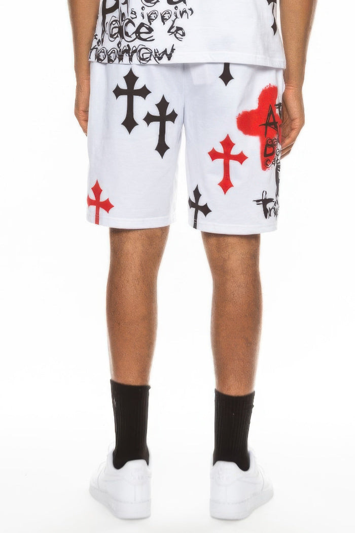 Person wearing white shorts with black and red cross designs on a white background