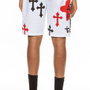 Person wearing white shorts with black and red cross designs on a white background