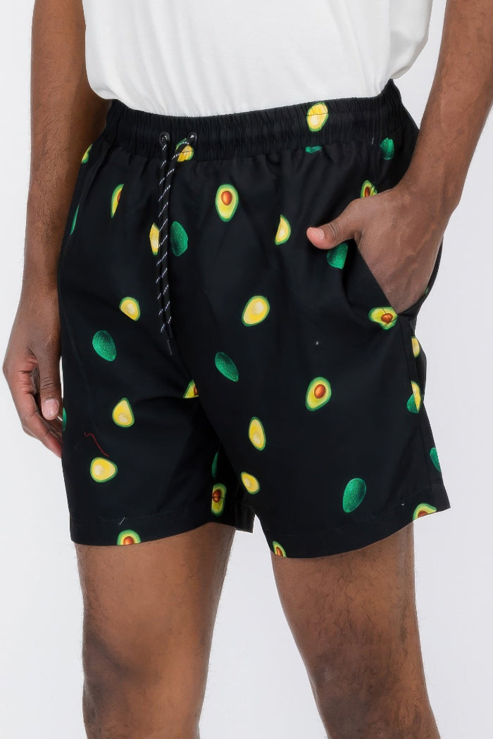 Person wearing black shorts with avocado pattern on a white background
