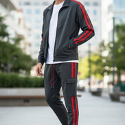 Man wearing a gray tracksuit with red stripes taken ouside