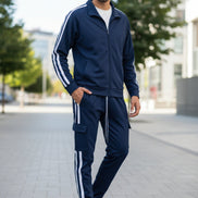 Person wearing a navy tracksuit with white stripes taken outside