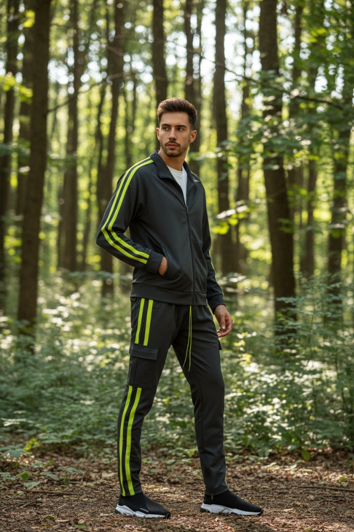 Man wearing a gray tracksuit with yellow stripes  taken outside