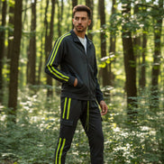 Man wearing a gray tracksuit with yellow stripes  taken outside