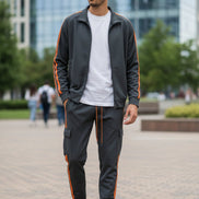Man wearing a gray tracksuit with orange stripes  taken outside
