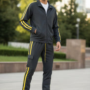 Man wearing a gray tracksuit with yellow stripes taken outside