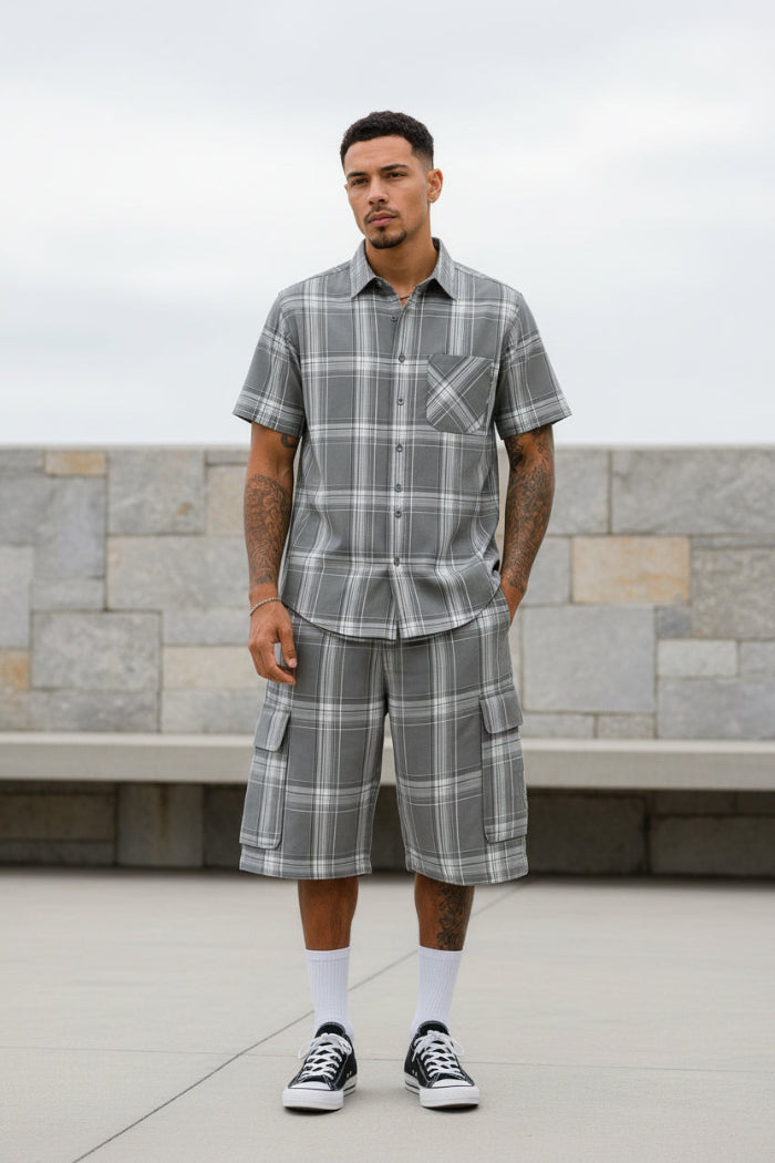 Man wearing a gray plaid shirt and shorts taken outside