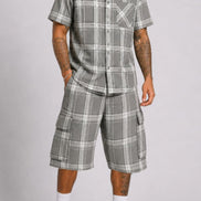Man wearing a gray plaid shirt and shorts set on a plain background