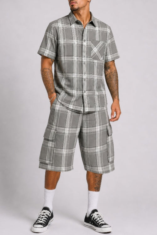 Man wearing a gray plaid shirt and shorts set on a plain background